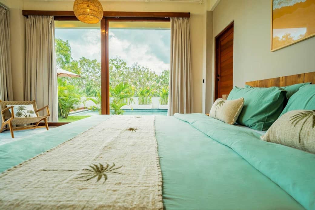 Wake up to views of lush greenery and the pool just steps away. This serene bedroom offers direct garden access and floor-to-ceiling windows, blending indoor comfort with tropical beauty for a truly relaxing stay.