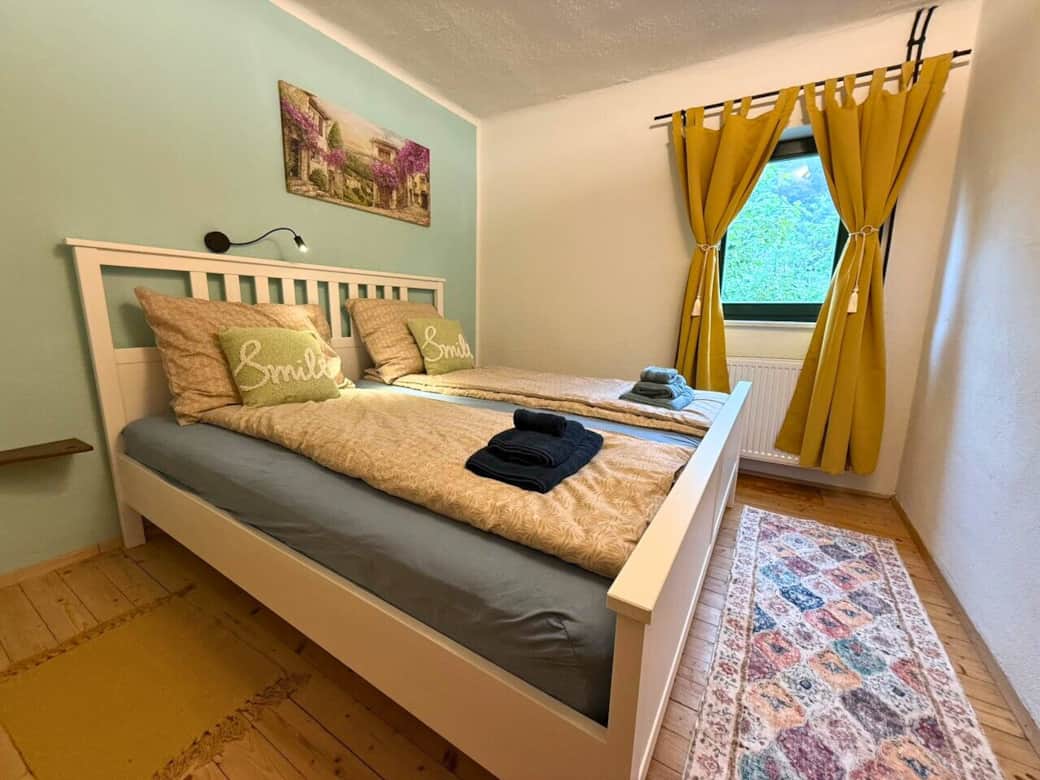 Schlafzimmer mit Doppelbett, Kleiderschrank und Spiegel. Fenster mit AUsblick auf den Fluss