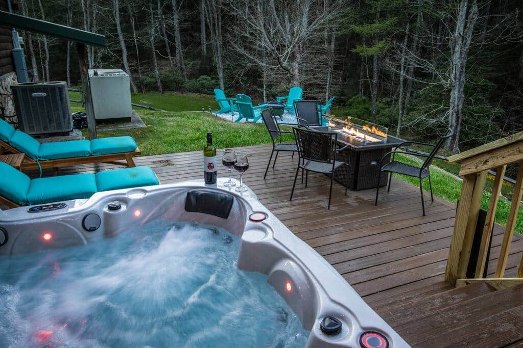 The hot tub and lounge chairs are right below the outdoor dining area, leading to the back yard