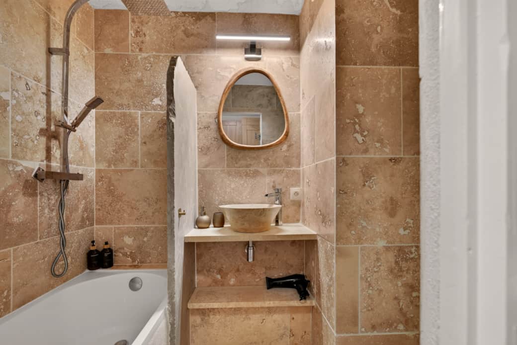 Travertine bathroom: sculpted stone sink and wooden mirror — a haven of well-being. Travertine bathroom: sculpted stone sink and wooden mirror — a haven of well-being.