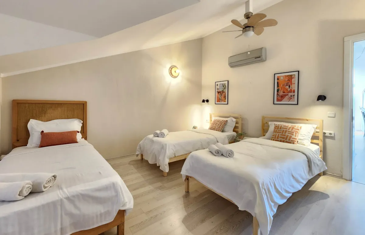 Bedroom with three single beds, decorative pillows, and wall art in Apart Guney 6, Gocek.