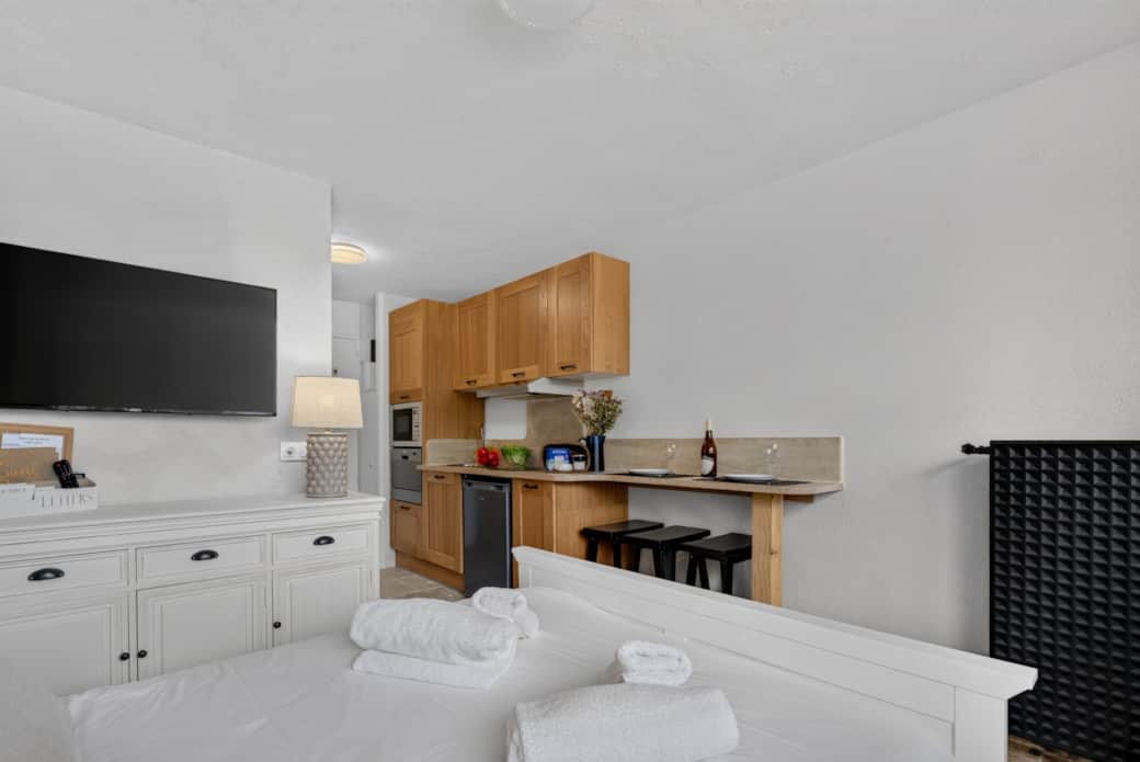 Overview of the studio: sleeping area, TV and kitchen in the background — optimized for 3 travelers. Overview of the studio: sleeping area, TV and kitchen in the background — optimized for 3 travelers.
