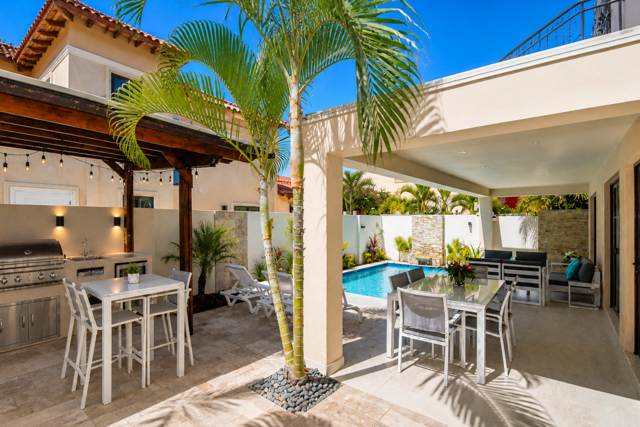 Fully-enclosed private backyard with pool, dining table, conversation set, BBQ, and bar table