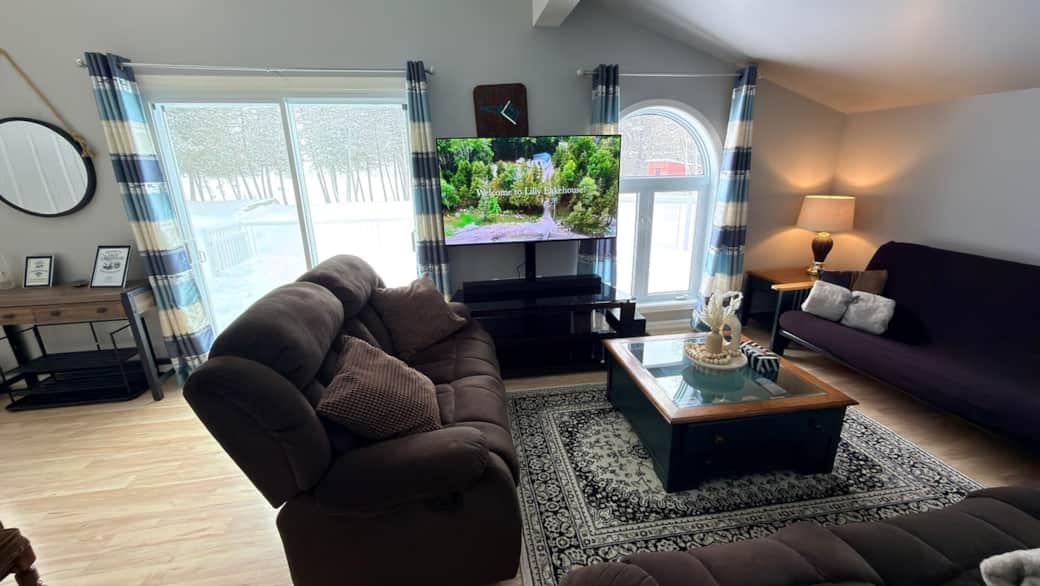 Open-concept living space featuring recliner sofas, large windows, and a 55” smart TV 