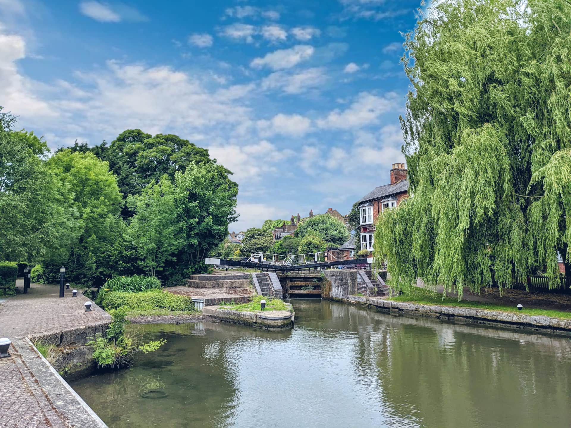 A historic canal lock situated directly outside a traditional waterside pub, showcasing beginner friendly routes available with luxury canal boat hire.