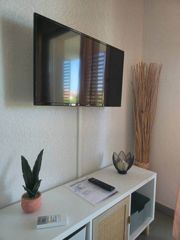 Salon lumineux avec TV écran plat et décoration moderne. Espace convivial, idéal pour se détendre ou regarder un film en famille, parfait pour une soirée relax après vos balades sur la côte.