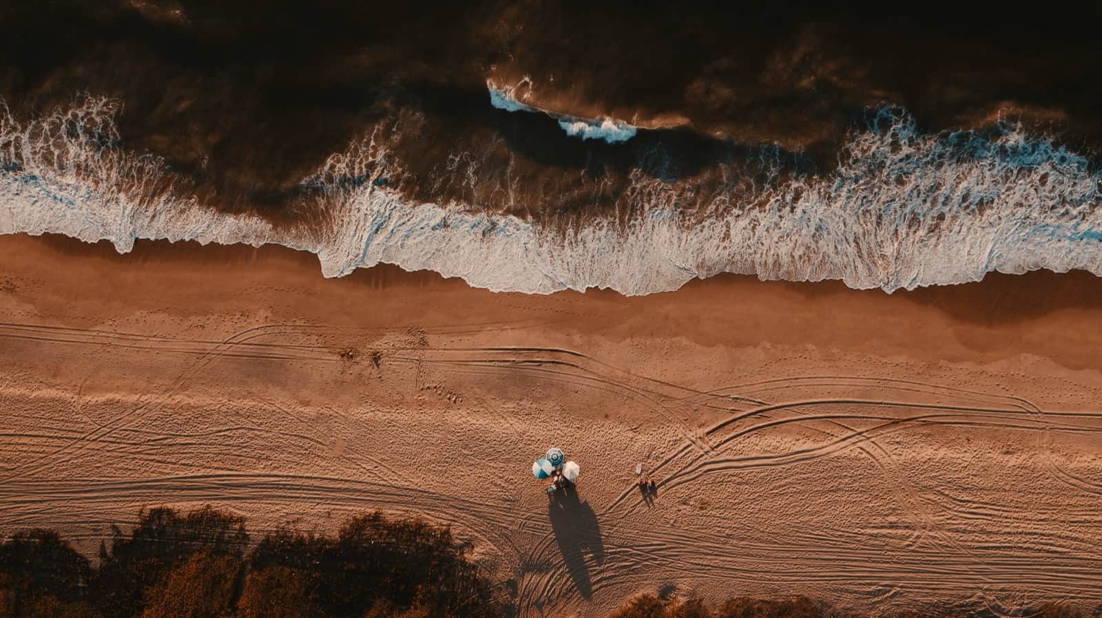 Aerial view of waves, sand, and beach umbrellas near La Peñita de Jaltemba, Riviera Nayarit