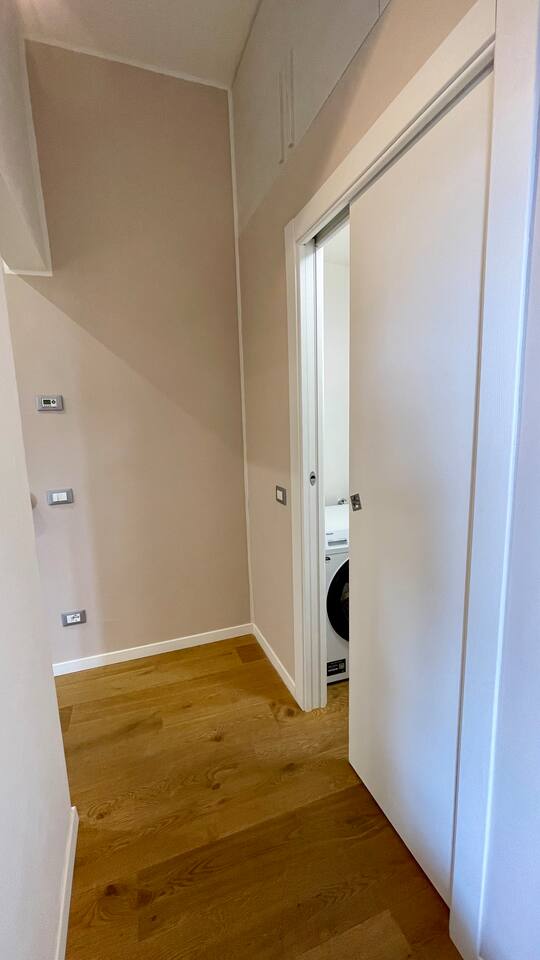 Zona lavanderia con lavatrice Haier da 8 kg, lavatoio, stendibiancheria, ferro da stiro, tavola da stiro e prodotti per la pulizia.