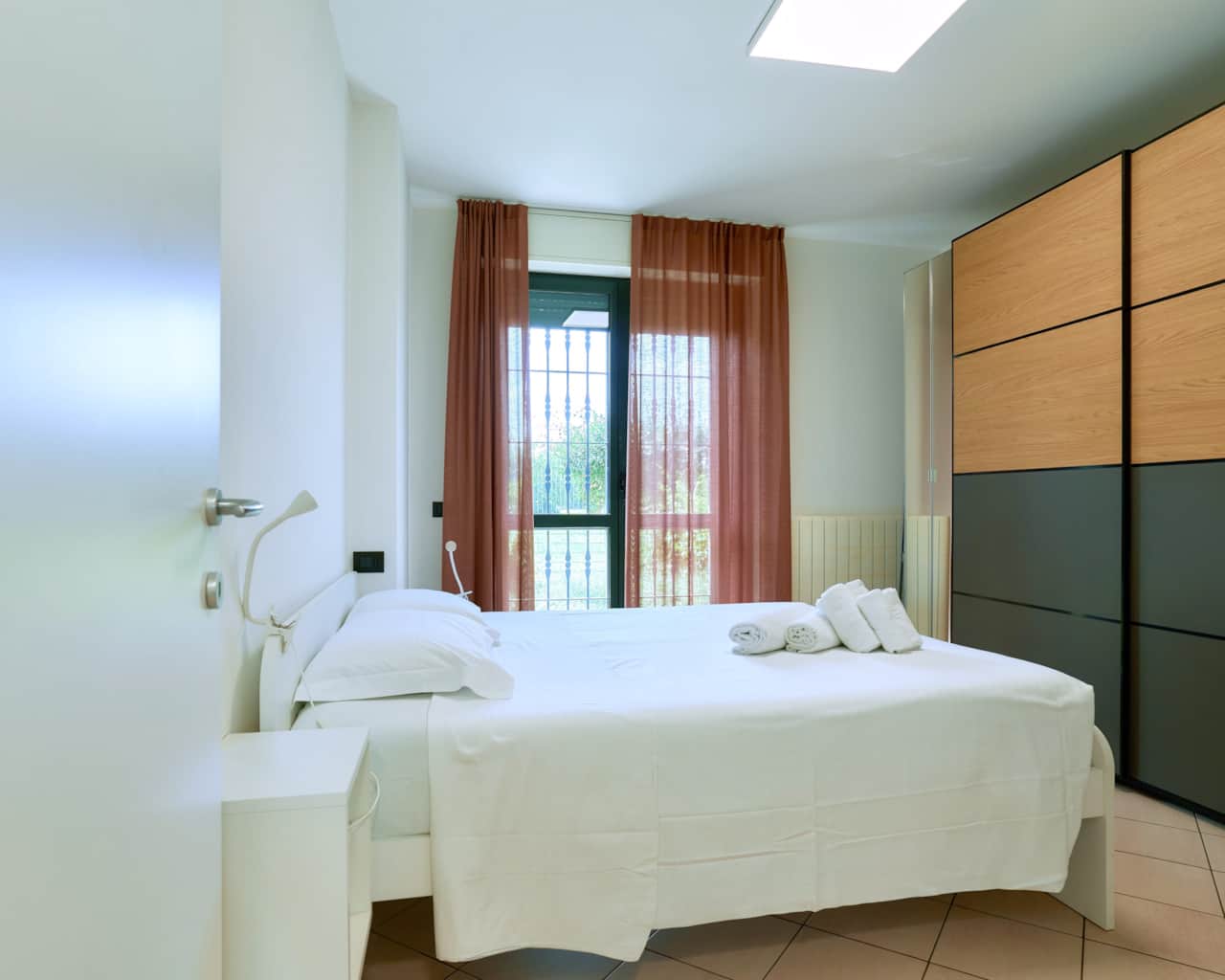 Dormitorio con cama de matrimonio, armario y cortinas rojas