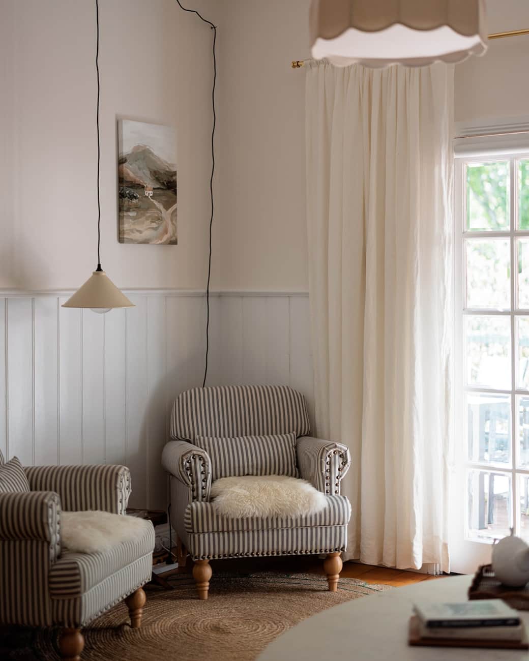 A comfortable armchair, books, and hanging lights create a warm, welcoming space.   