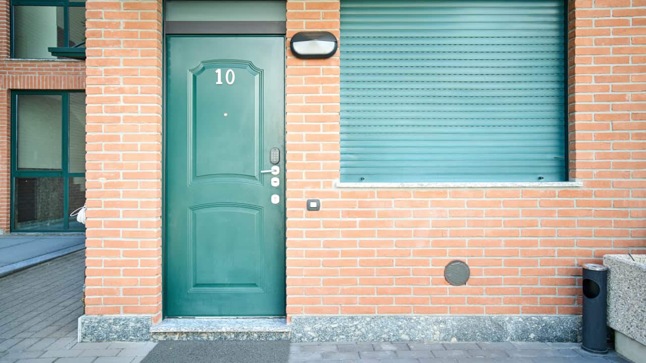 Green front door on a brick façade, in Monza