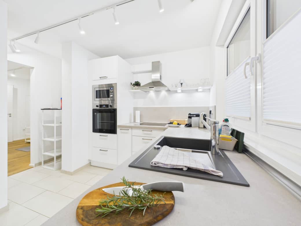 Moderne helle, voll ausgestattete Küche mit Backofen, Mikrowelle und viel Arbeitsfläche.