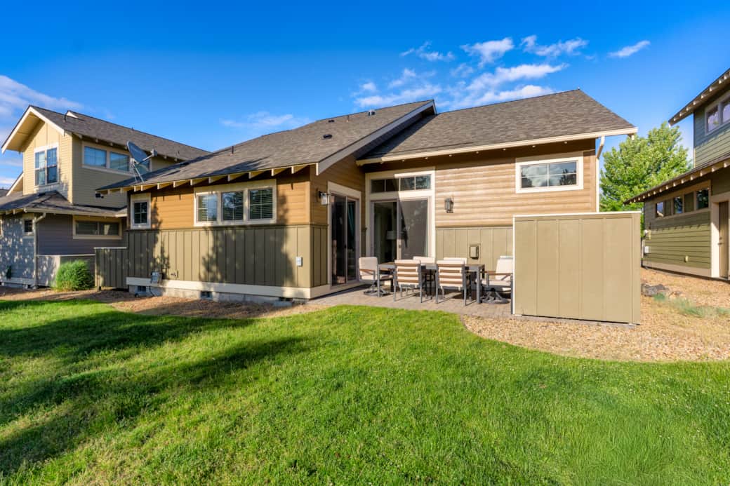 Rear exterior with private patio, green lawn, and ponderosa pine setting.