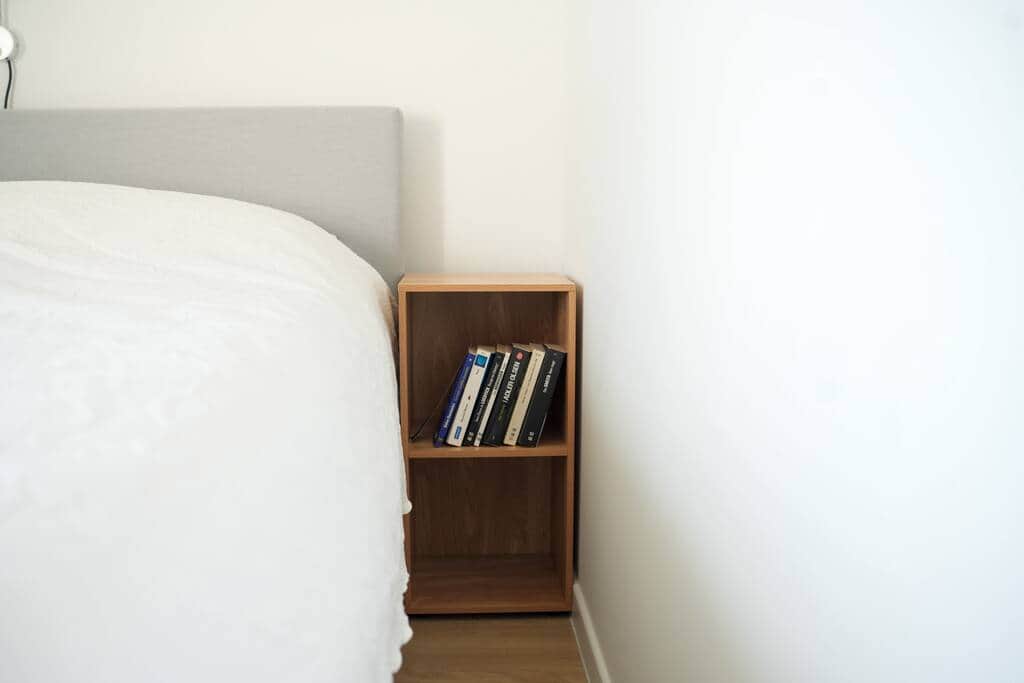 Chambre lit double, oreillers et couette, et une petite commode.