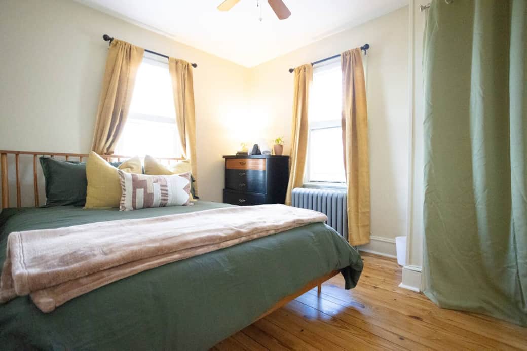 Unwind in this serene bedroom featuring a plush queen bed, cozy layers of pillows and blankets, and calming colors that invite rest and relaxation