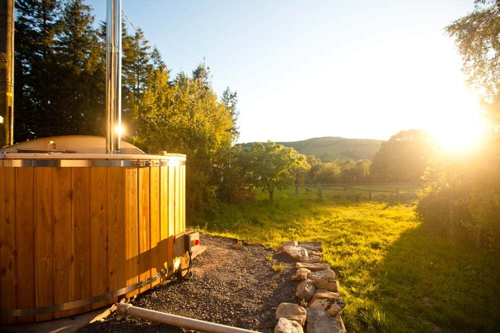 Private wood-fired hot tub overlooking the meadow at sunset