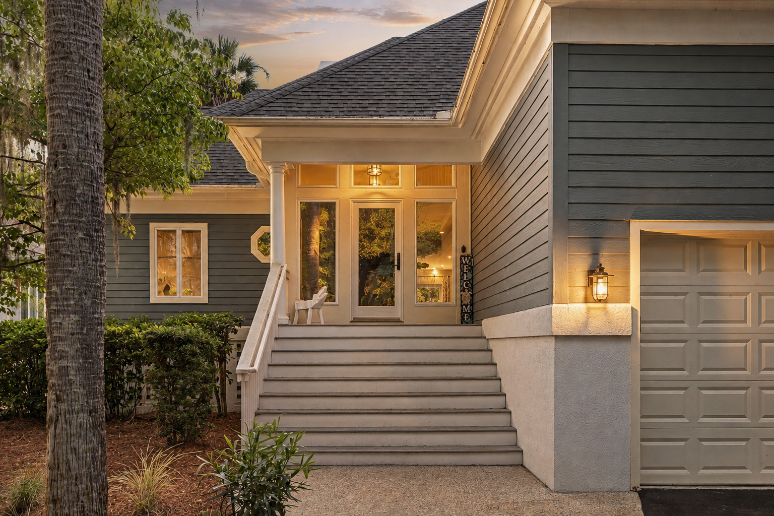 Follow the steps to the welcoming front entrance, softly lit and tucked among the surrounding greene