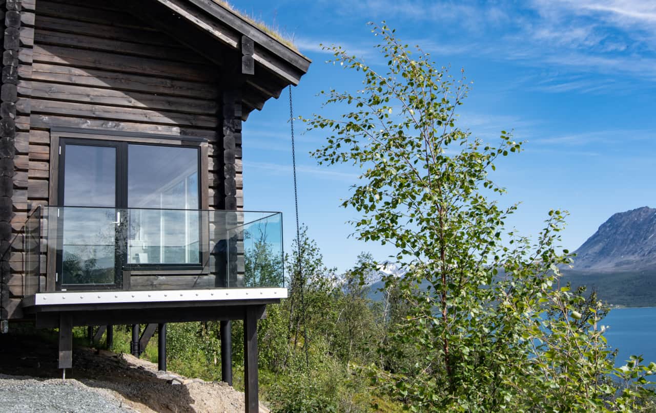 Nordlys vacation home facade with birch trees and Arctic mountain view