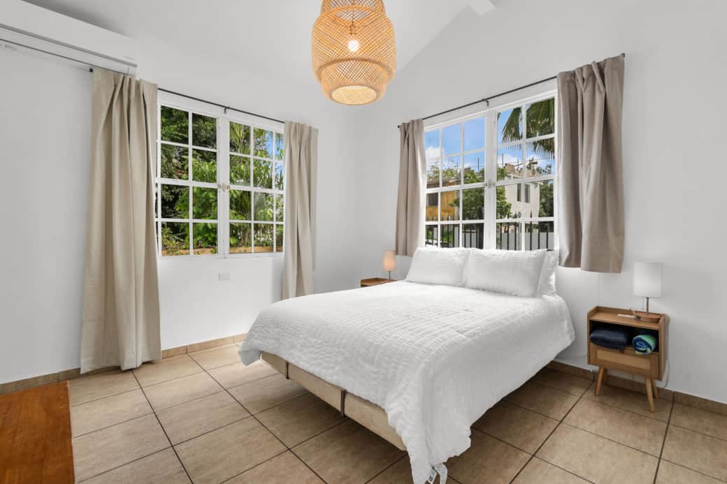 Bright primary bedroom with queen bed, AC, black out curtains, and an ensuite bathroom