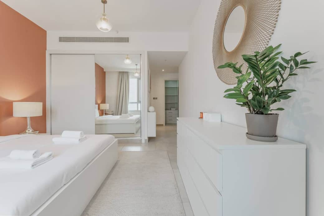 Elegant bedroom with large windows, ambient lighting, and ample closet space ideal for restful nights in a stylish urban retreat.
