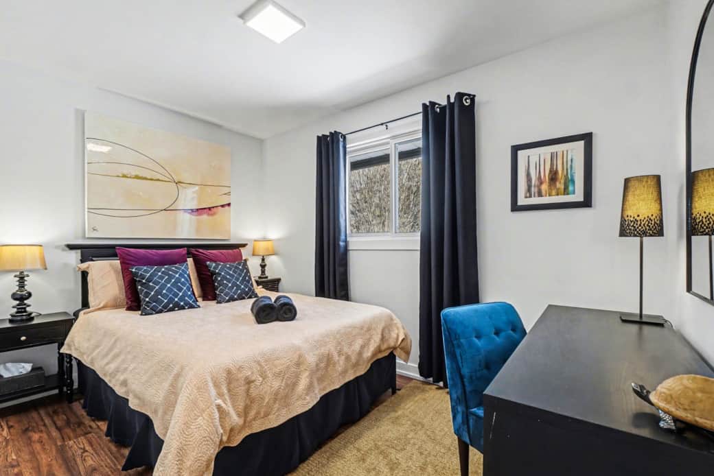 Cozy primary bedroom with queen bed, dedicated workspace, and warm lighting in Ottawa