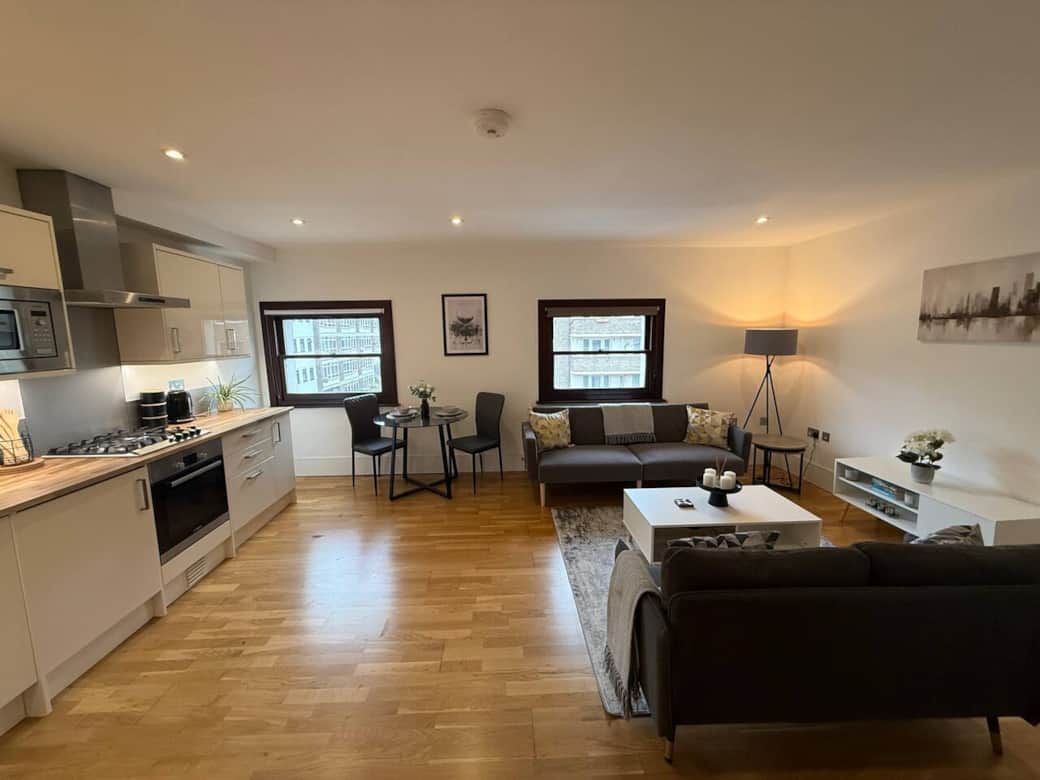 Bright open-plan living room with comfortable seating, Smart TV, dining area for meals or work, and a fully equipped modern kitchen. Spacious social area ideal for relaxing after a day in London. Bright open-plan living room with comfortable seating, Smart TV, dining area for meals or work, and a fully equipped modern kitchen. Spacious social area ideal for relaxing after a day in London.