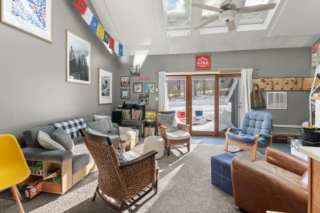 Sun-soaked seating surrounds a charming fireplace, perfect for après-ski evenings! Ski-In/Ski-Out and tubing right out the back deck.  Ski and coat racks in the corner for gear and firewood stacked in vintage ski tower.  