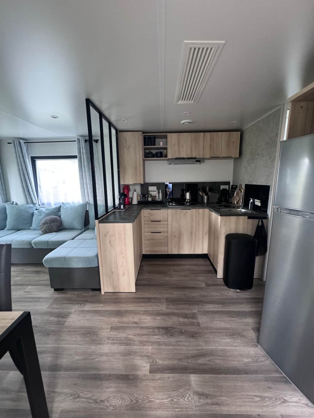 Wohnraum mit Sofa, Küche, Esstisch, Ausgang zur Terrasse und Blick auf den See