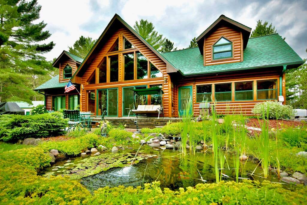 The chalet and patio, with an adjoining pond and waterfall, overlook the large yard and lake.