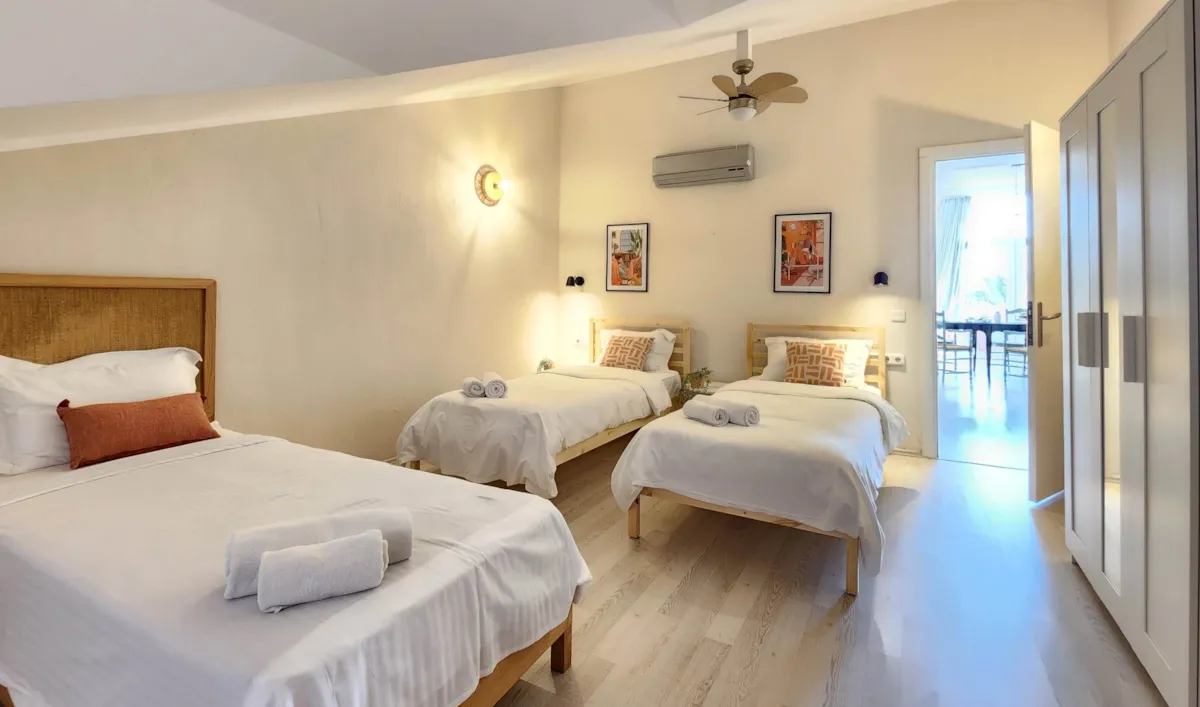 Bedroom with two single beds and one double bed, featuring a wardrobe and wall art, Apart Guney 6, Gocek.