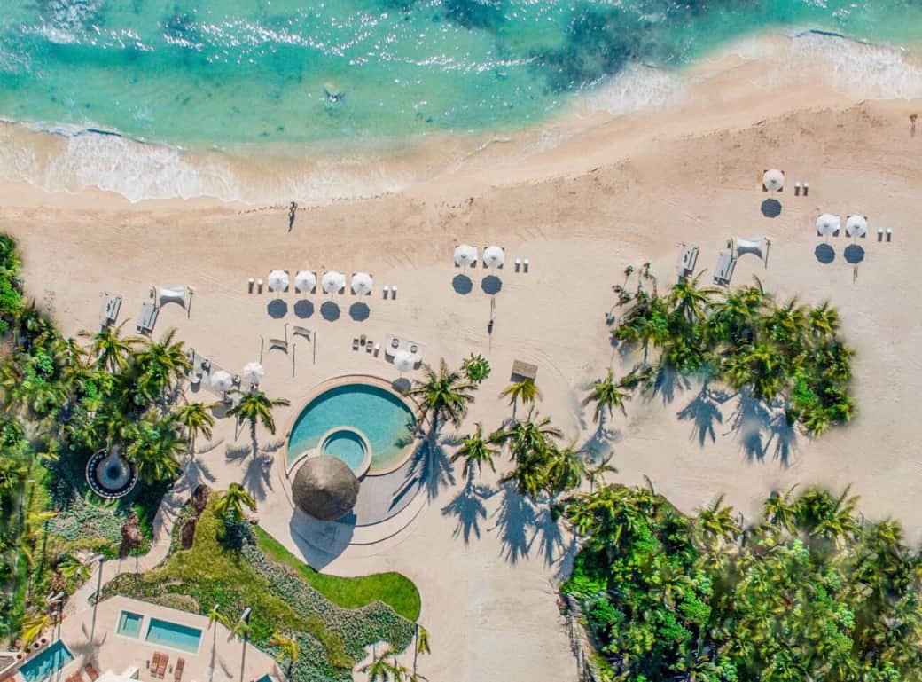Costa Beach Club offers a beautiful beachfront setting with pools, loungers, and a swimmable beach, accessible with a $100 USD minimum spend per person that can be used at restaurants, bars, spa services, yoga classes, kids club, or the onsite store.