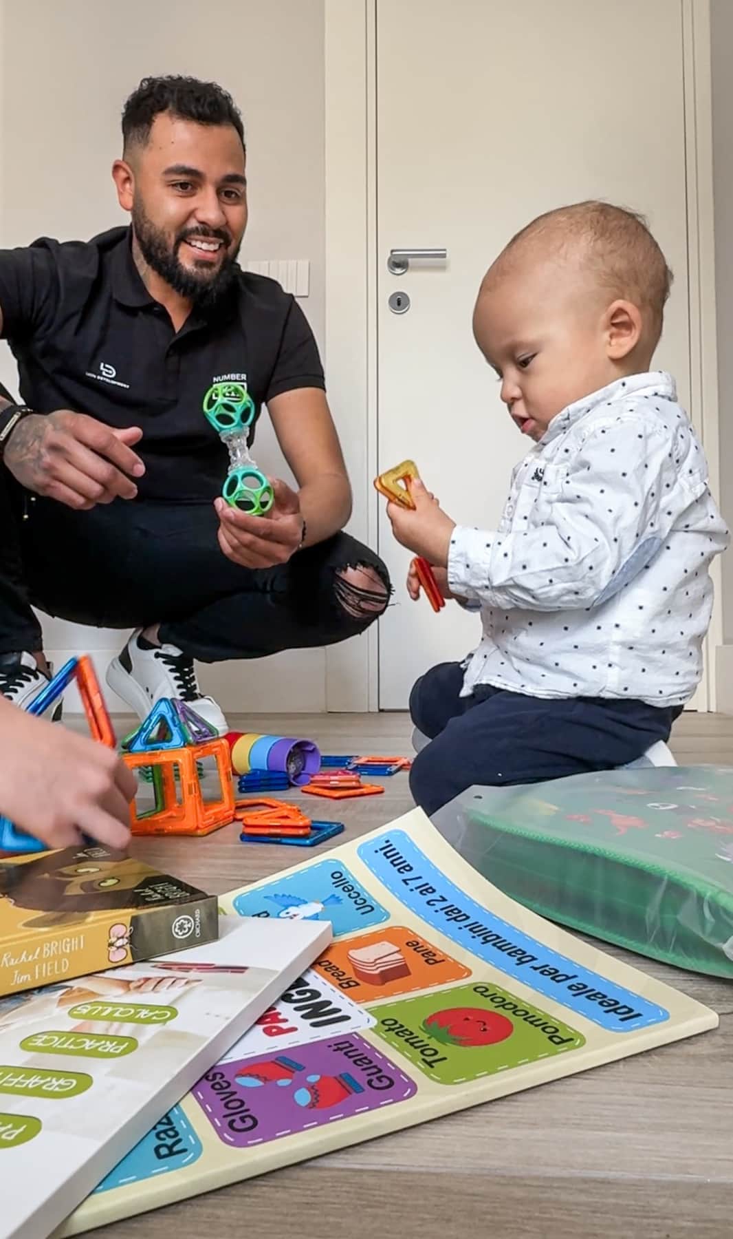 Father playing with baby using toys supplied free by RENTAL12 family welcome kit in Olbia