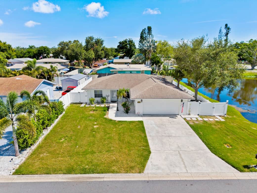 An aerial view of Casita Haven Retreat showcases a spacious corner lot with a private driveway, lush landscaping, a peaceful lakeside setting and a quiet neighborhood, offering both privacy and a relaxing Florida getaway.