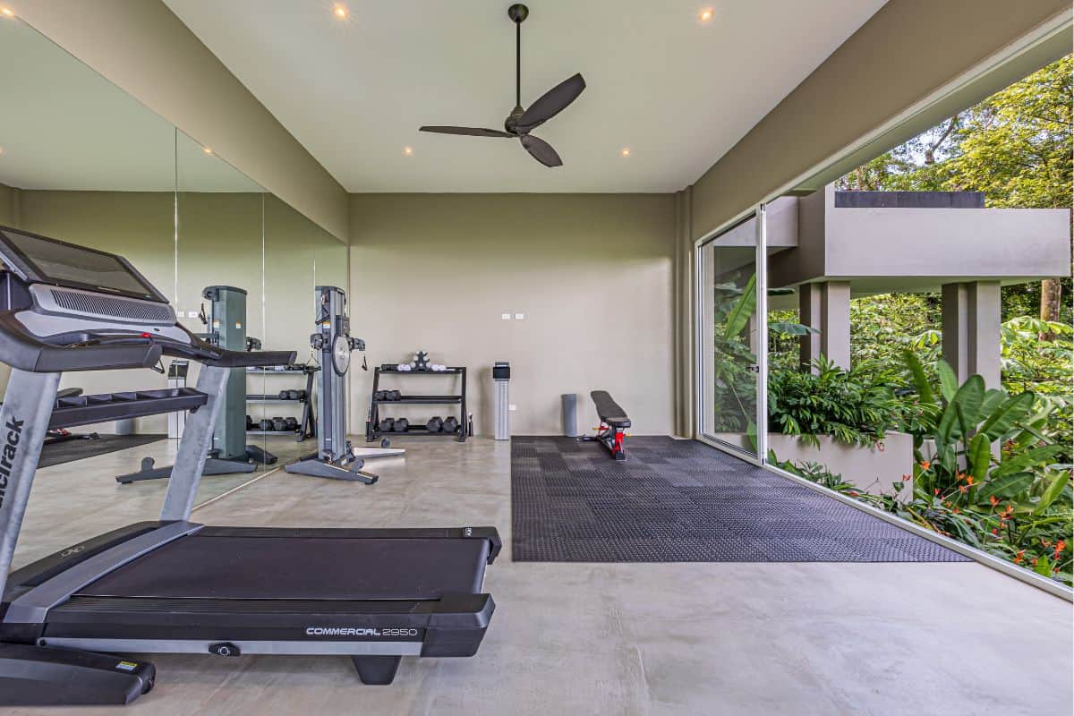 Private gym at Villa Sueño with panoramic jungle views through floor-to-ceiling glass walls.