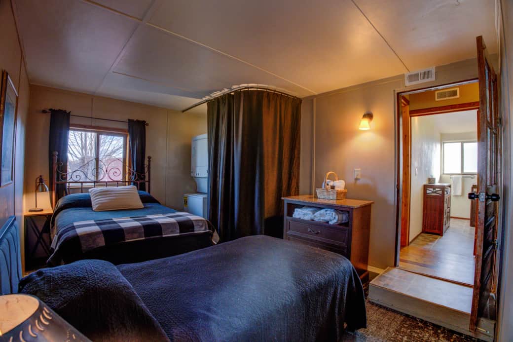 Bedroom 2 with 2 beds and the washer/dryer peaking out from the curtained closet.