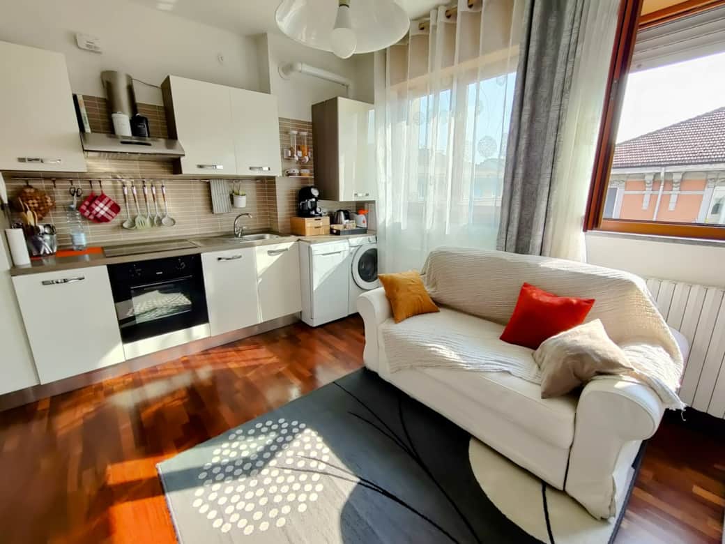 Living room with sofa bed and kitchen equipped with washing machine and dishwasher