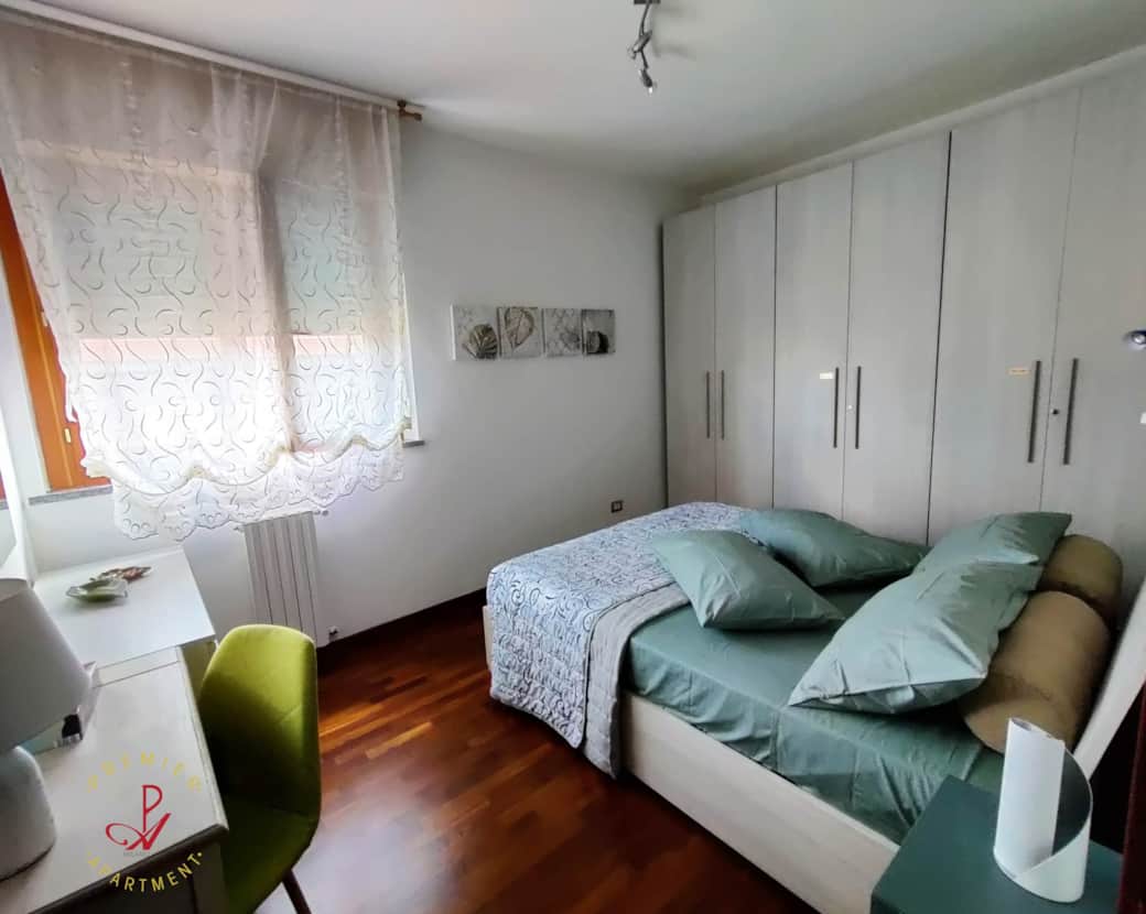 Dormitorio luminoso con suelo de parquet, escritorio, cómoda y armario.