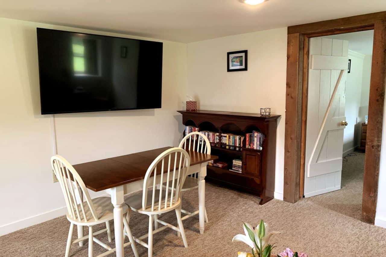 Great room includes a dining area, 65" smart TV, a comfy seating area, books, games, puzzles