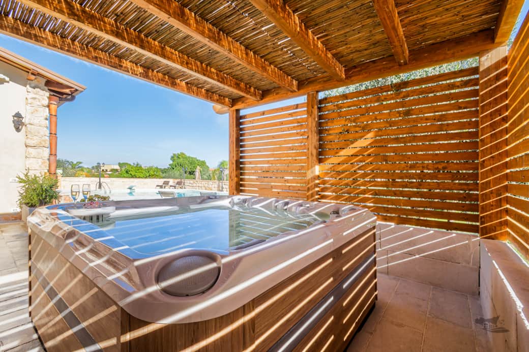 Unwind in the private heated hot tub, sheltered under a charming wooden pergola with a pool view.