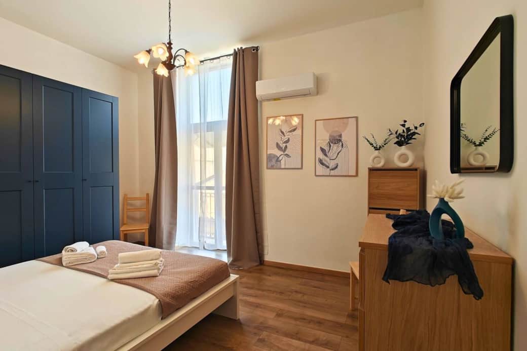 Camera accogliente con letto queen size, prese comode accanto al letto, ampio armadio. Porta finestra con accesso diretto al balcone — il comfort incontra la praticità