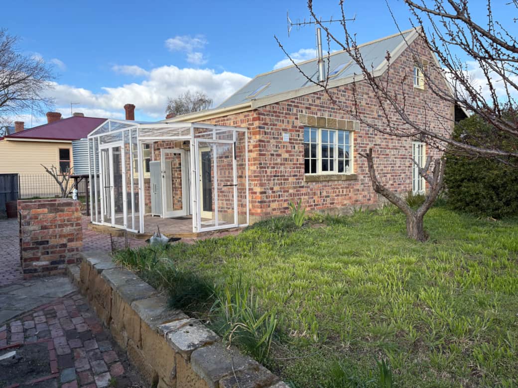 Enjoy the generous garden space and light-filled sunroom, set against the home’s historic brickwork.