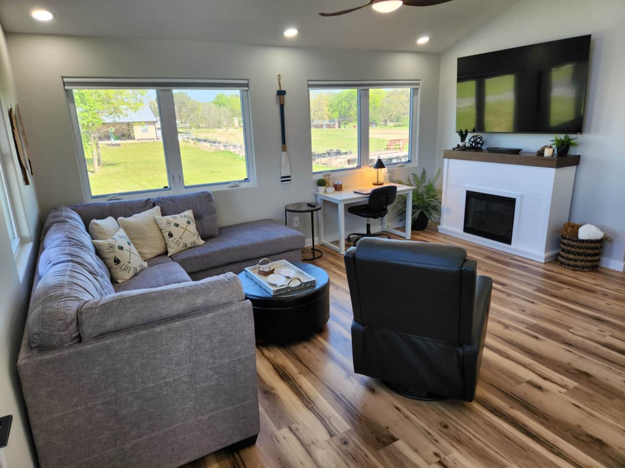 Living room with 75" 4K HDTV, electric fireplace with heater, and work desk with comfortable chair.