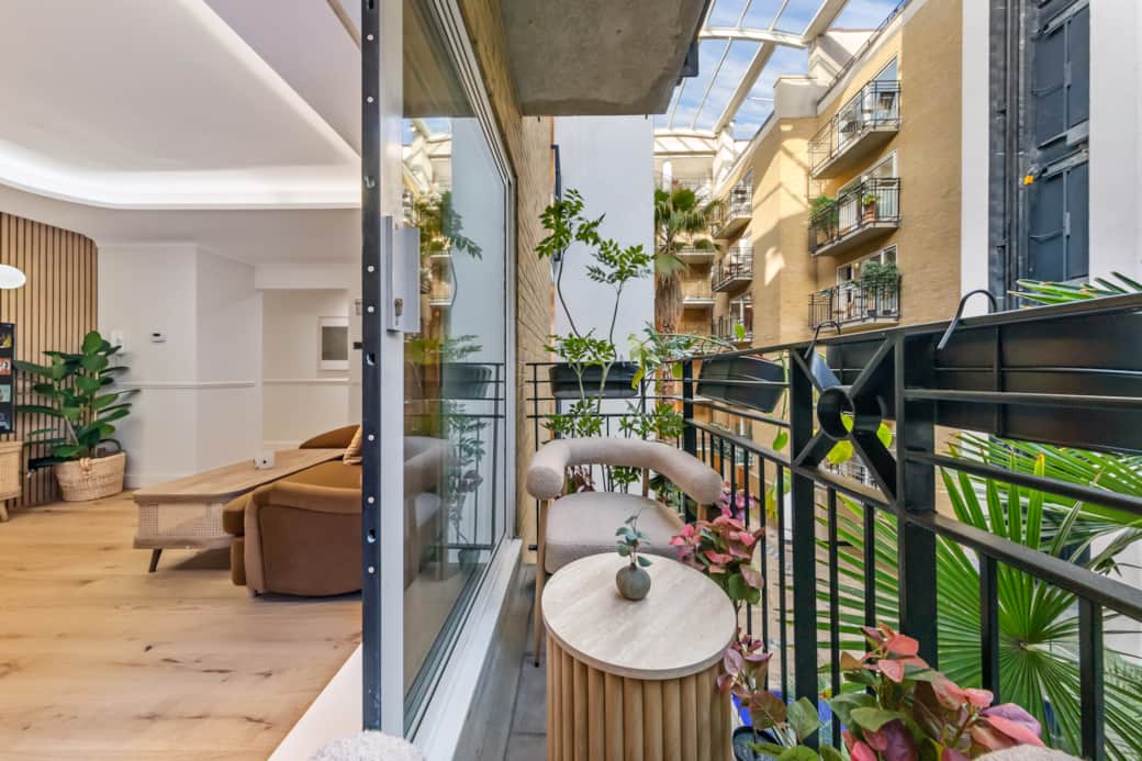 Compact balcony with seating and plants, overlooking a quiet courtyard Compact balcony with seating and plants, overlooking a quiet courtyard