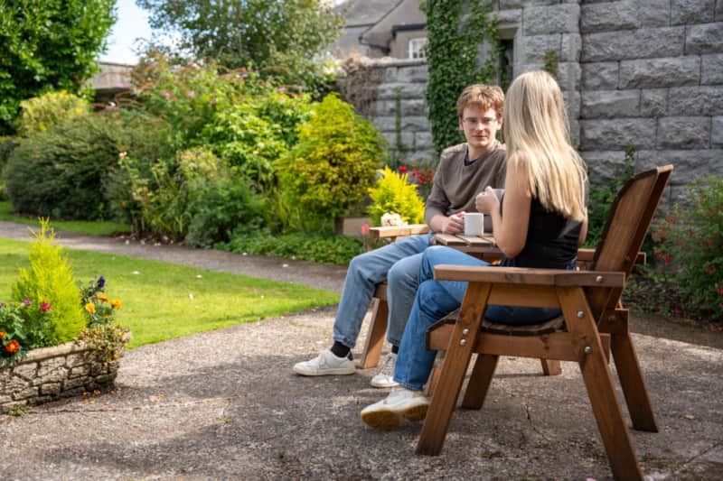 A couple with mugs of coffee at a wooden table in the Secret Garden