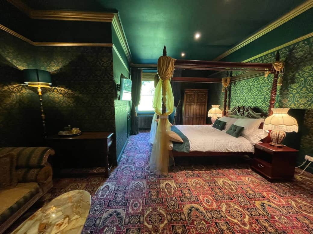 Green and gold bedroom with king size four poster bed with En Suite. 
Has TV, wifi, sofa and table with tea and coffee making facilities. 
Wardrobe with hangers, dressing table with mirror. 