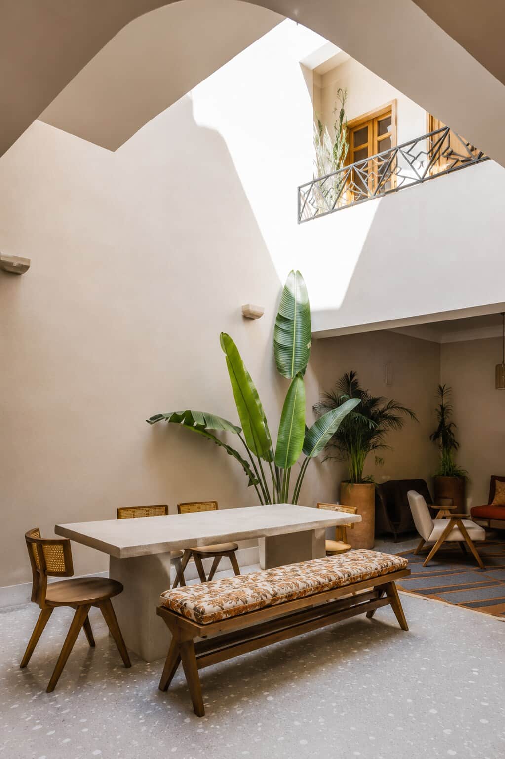La salle à manger et le patio en enfilade : table de pierre, banc chiné, banane du Yémen. Lumière zénithale toute la journée.