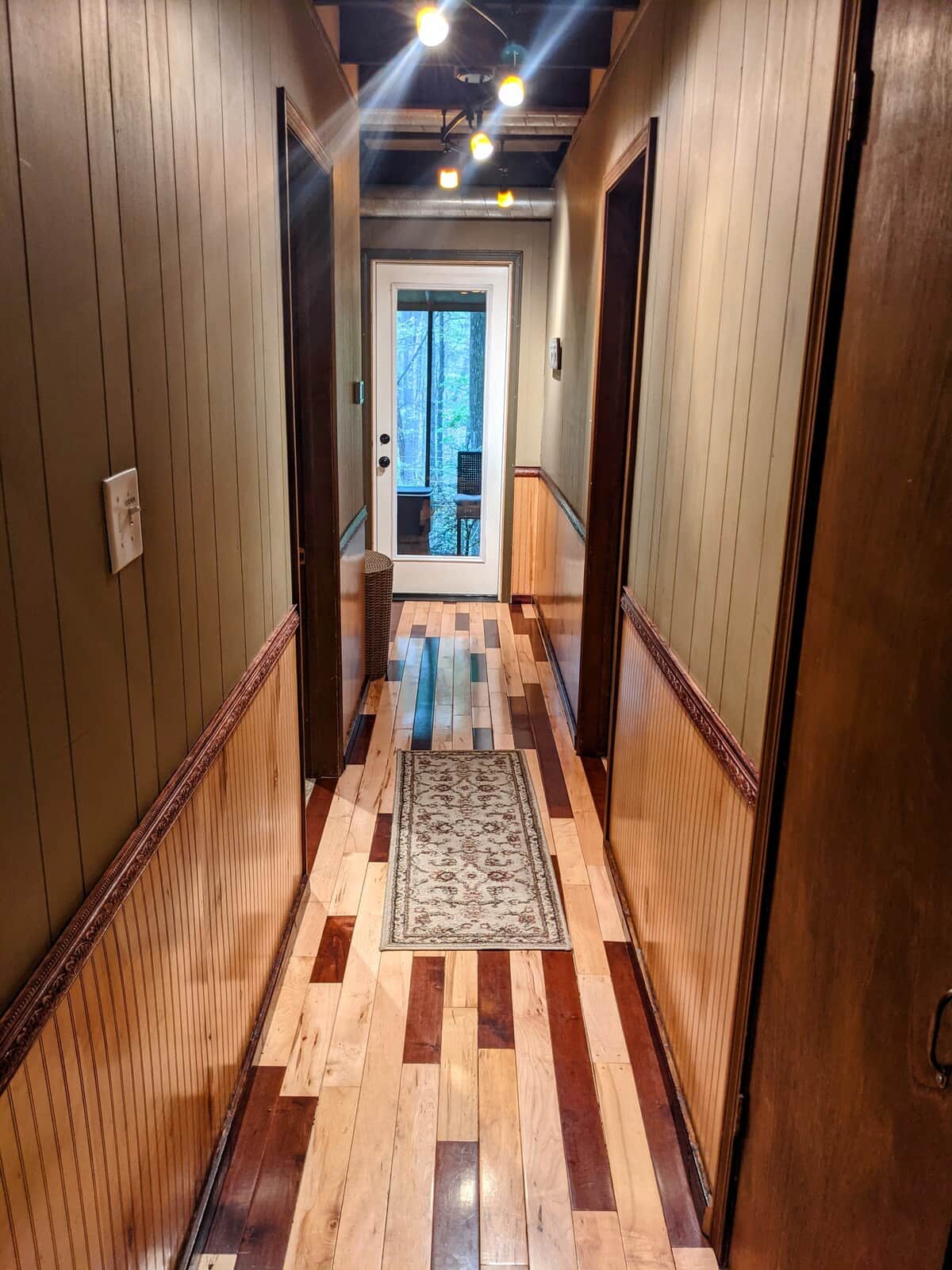 Down stairs hallway. Door on the left is the bathroom. Door on the right is down stairs bedroom. Door straight ahead leads to back screened in porch/deck 
