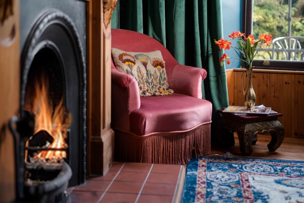 Eccentric Caterpillar lounge: Teal/blue walls, velvet sofa, fireplace, and cozy reading nook.