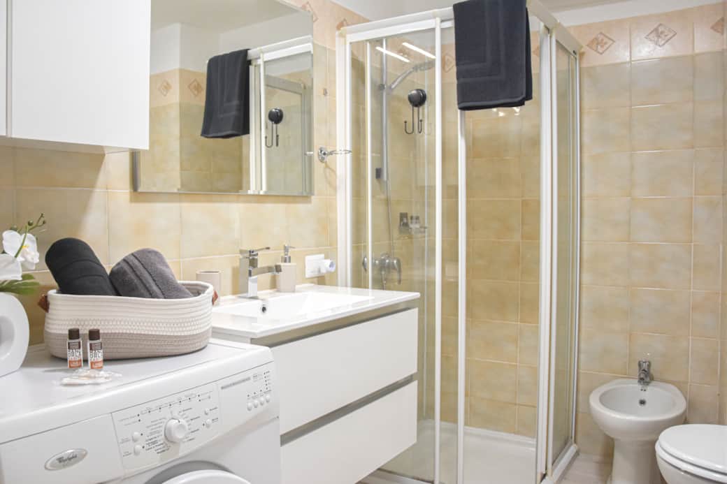 Bagno con lavatrice, doccia, asciugamani e asciugacapelli