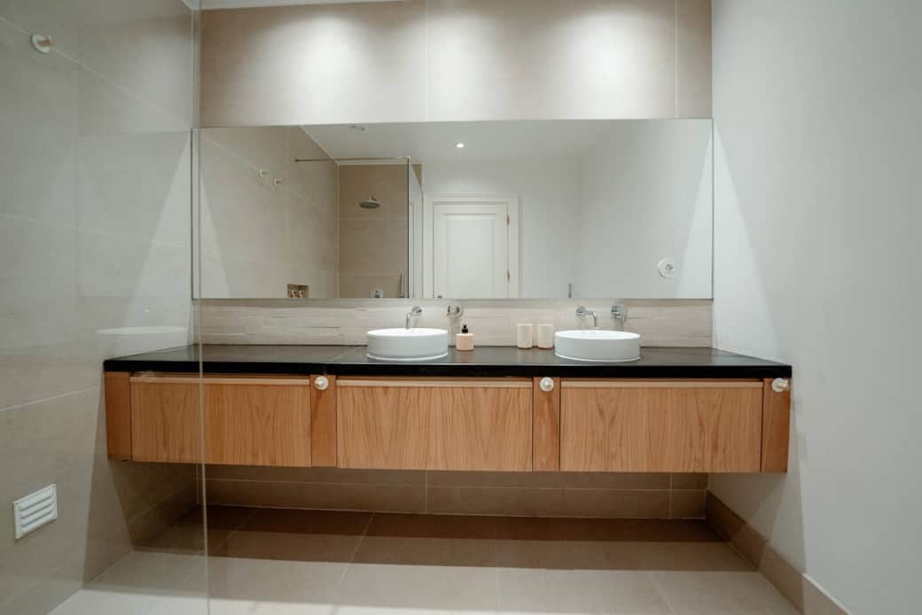 A casa de banho de bancada em madeira de carvalho, é acompanhada por espelhos grandes A casa de banho de bancada em madeira de carvalho, é acompanhada por espelhos grandes